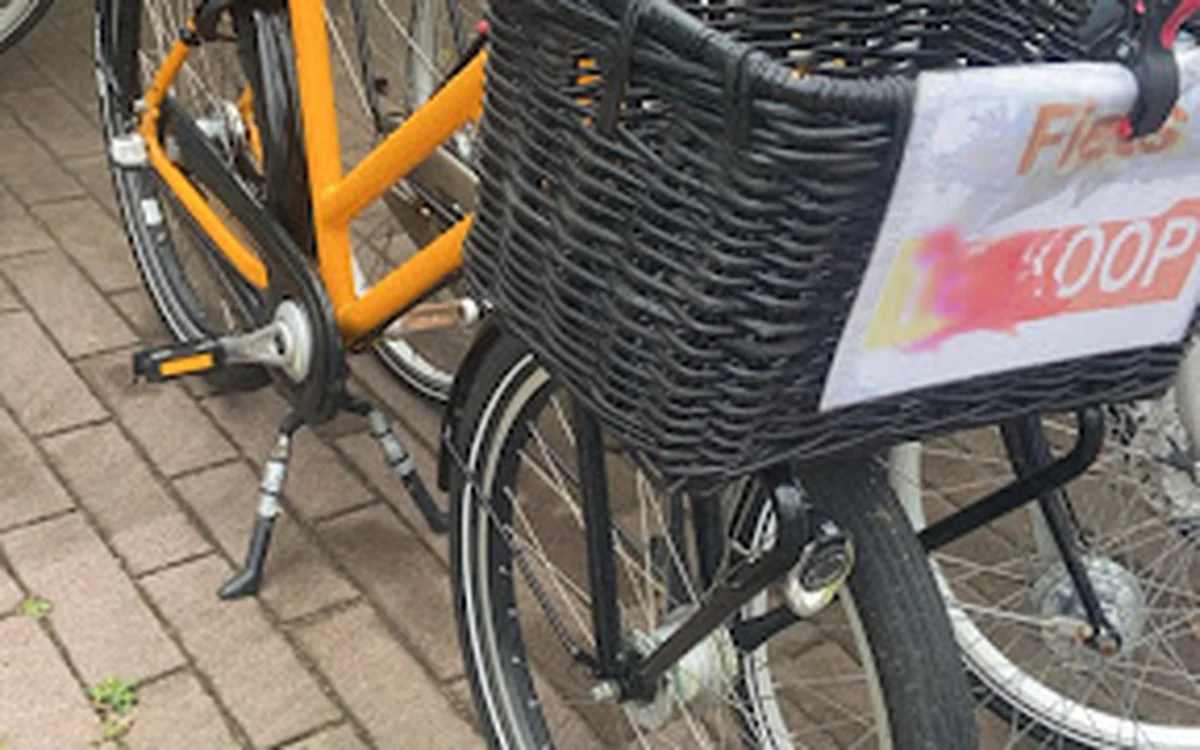 Tweedehands fietsen met mand, waaronder een oranje fiets en een fiets met winkeltas