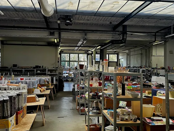 Ruim winkelinterieur met stellingen vol spullen, tafels met uitgestalde items en natuurlijk licht van boven