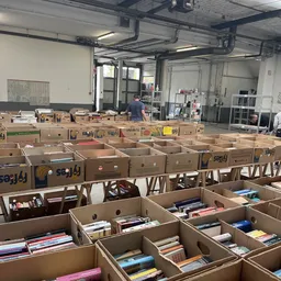 Grote aantallen kartonnen dozen en kratten met boeken en media uitgestald in de winkel