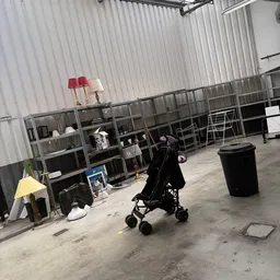Magazijnruimte met stellingen vol spullen, een kinderwagen en diverse voorwerpen op betonnen vloer