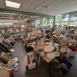 Winkelvloer met diverse meubels, huishoudartikelen en spullen uitgestald tussen stellingen en dozen