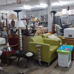 Winkelvloer met meubels: groene fauteuil, lampen, tafels en diverse huishoudelijke artikelen
