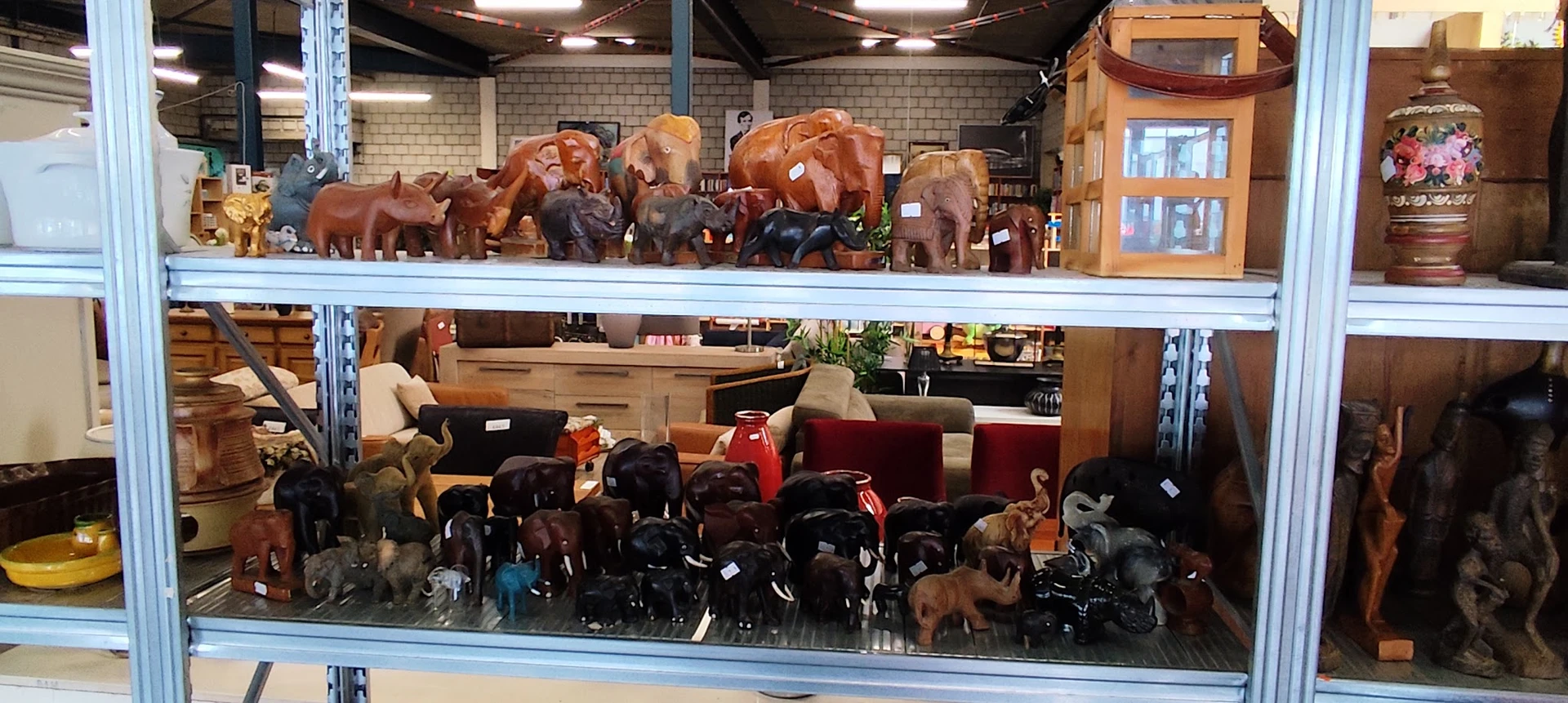 Stellingen met houten beelden van olifanten en andere decoratieve dierenfiguren in verschillende maten en kleuren