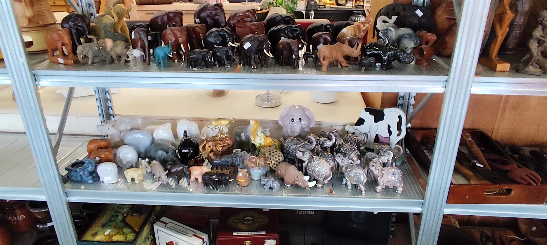 Vitrinekast met diverse decoratieve items: stenen dieren, kristallen, keramiek en kleine beeldjes