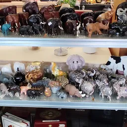 Vitrinekast met diverse decoratieve items: stenen dieren, kristallen, keramiek en kleine beeldjes