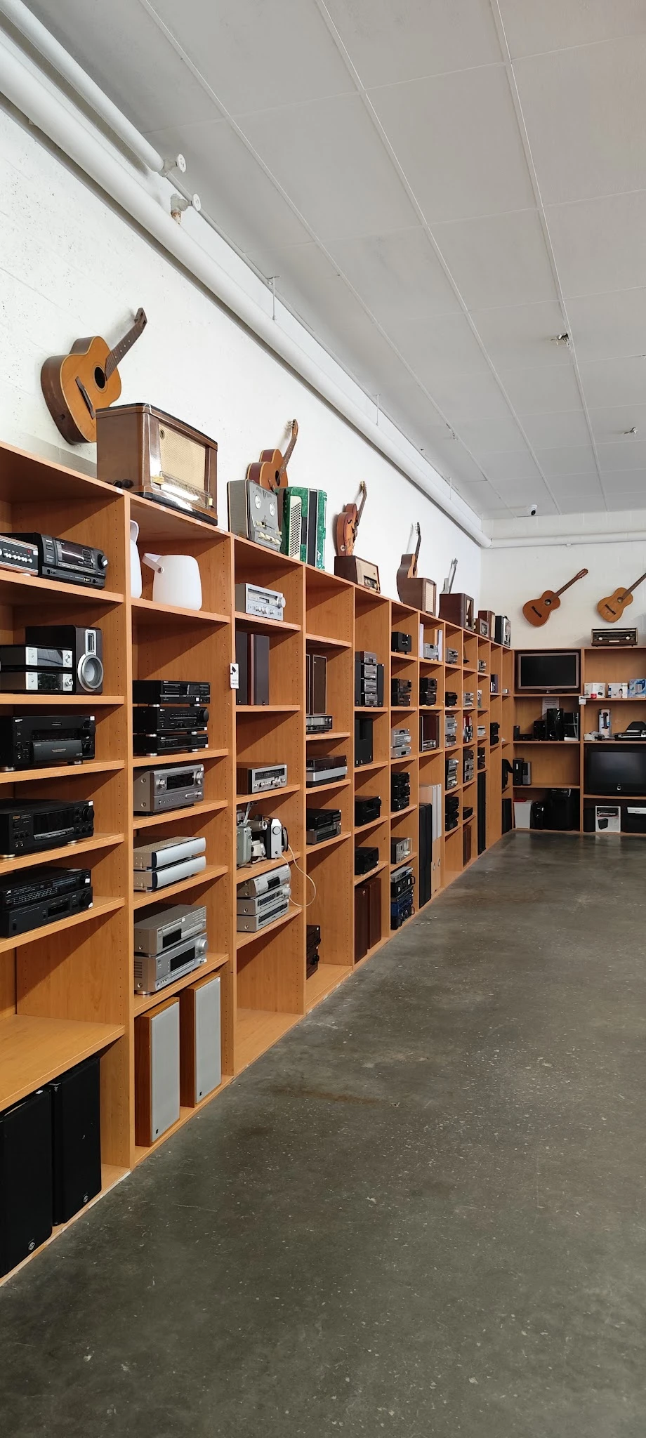 Houten stellingkasten met elektronische apparatuur en audiovisueel materiaal in een kringloopwinkel