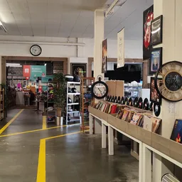 Winkelvloer met gele richtingslijnen, stellingen met boeken, vinyl records, klokken en decoratie aan de muur