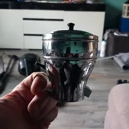 Glazen schaal met deksel en zwarte handgrepen, close-up in hand