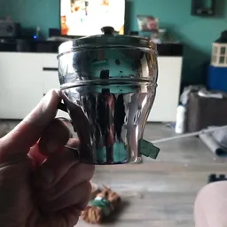 Doorzichtige kunststof beker met zwart deksel, gehouden in een hand