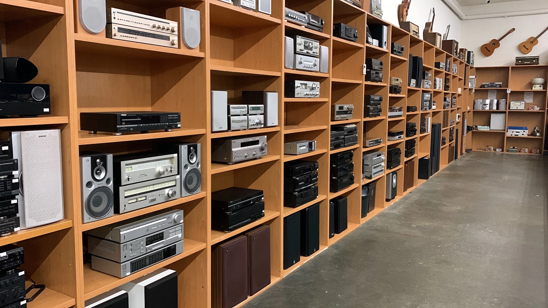 Grote houten stellingkast vol met vintage audio- en elektronicaapparatuur zoals versterkers, receivers en speakers