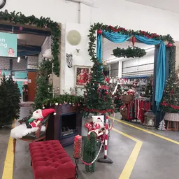 Kersversierde winkelruimte met groene guirlandes, rode decoraties, blauwe linten en kerstmanfiguren bij de ingang