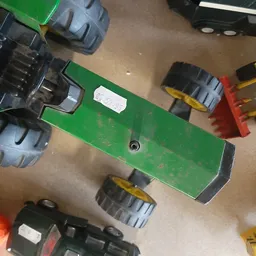 Groen speelgoedvoertuig met wielen gezien van bovenaf op betonnen vloer