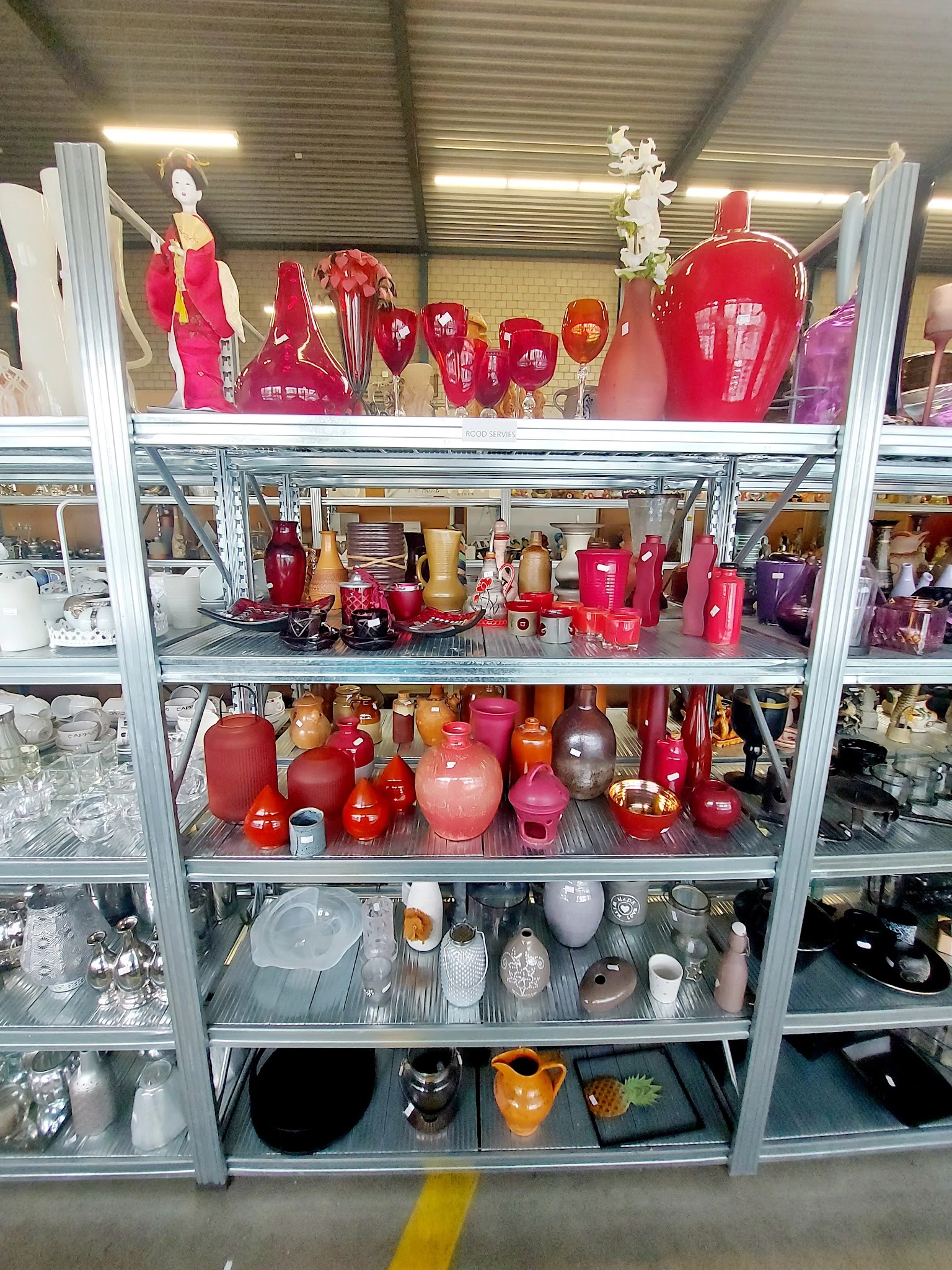 Stellingkast gevuld met rode en roze kaarsen in verschillende maten en vormen