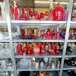 Stellingkast gevuld met rode en roze kaarsen in verschillende maten en vormen