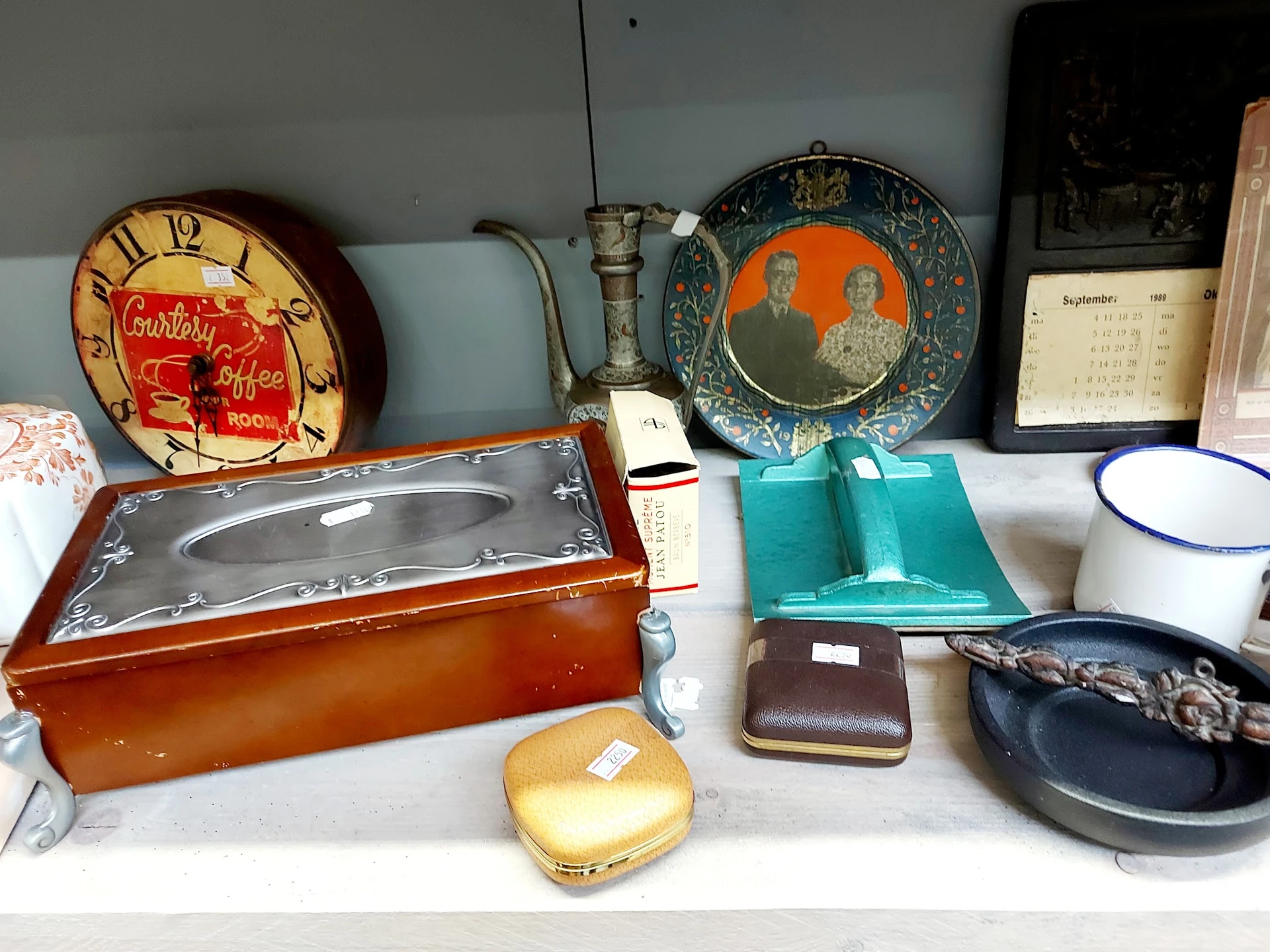 Uitgestalde vintage spullen: klokken, juwelendozen, portemonnees, servies en huishoudartikelen op een plank