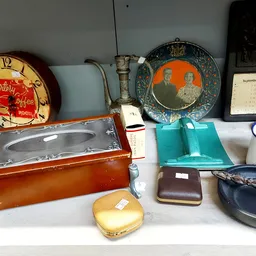 Uitgestalde vintage spullen: klokken, juwelendozen, portemonnees, servies en huishoudartikelen op een plank