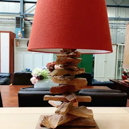 Houten decoratieve lamp met rode stoffen kap, opgebouwd uit gestapelde houten blokken