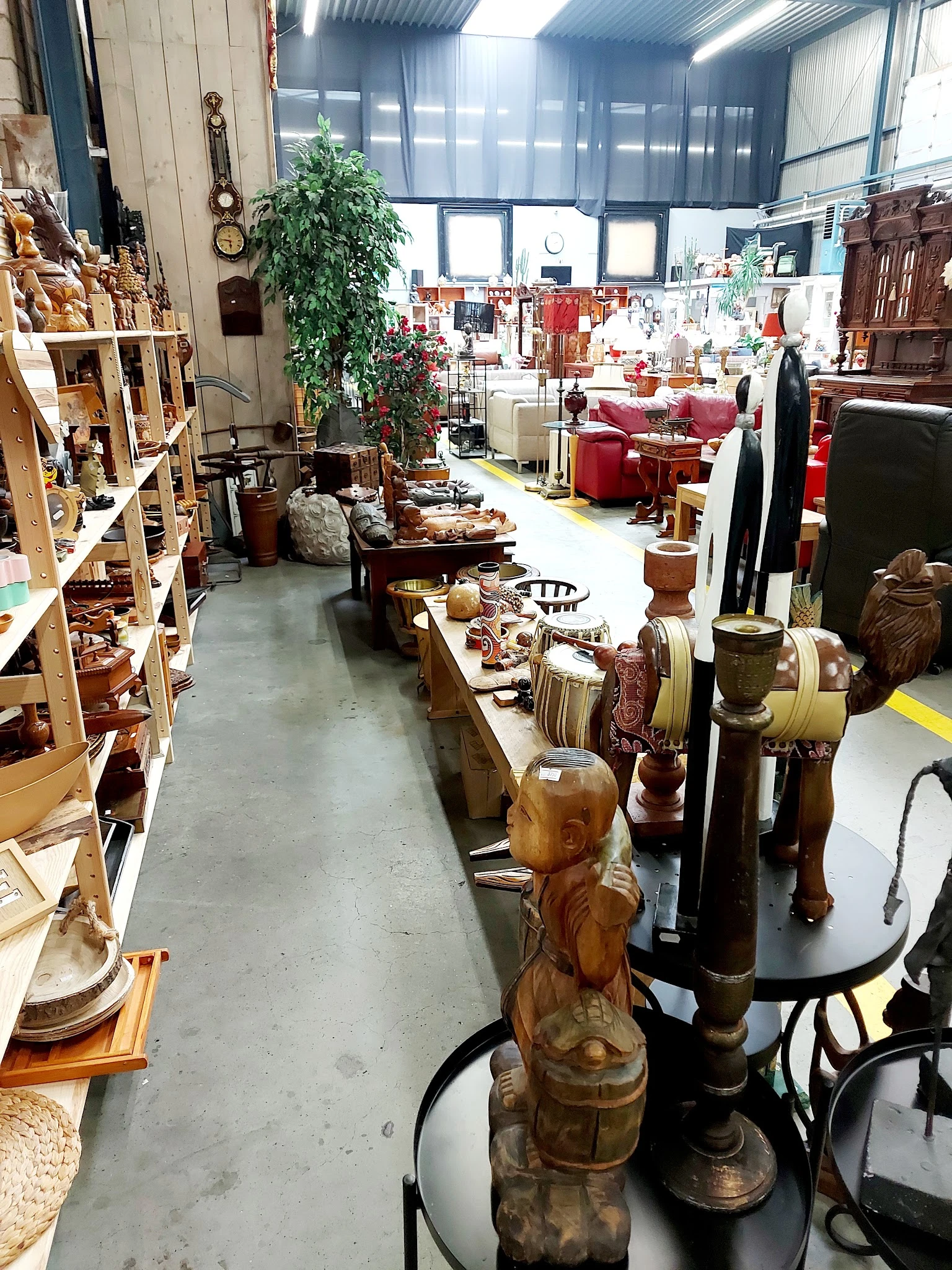 Winkelvloer met houten meubels, beelden en decoratieve objecten op tafels en stellingen