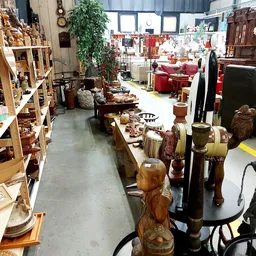 Winkelvloer met houten meubels, beelden en decoratieve objecten op tafels en stellingen