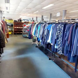 Rekken met tweedehands kleding, vooral jassen en jasjes in blauwe en paarse tinten