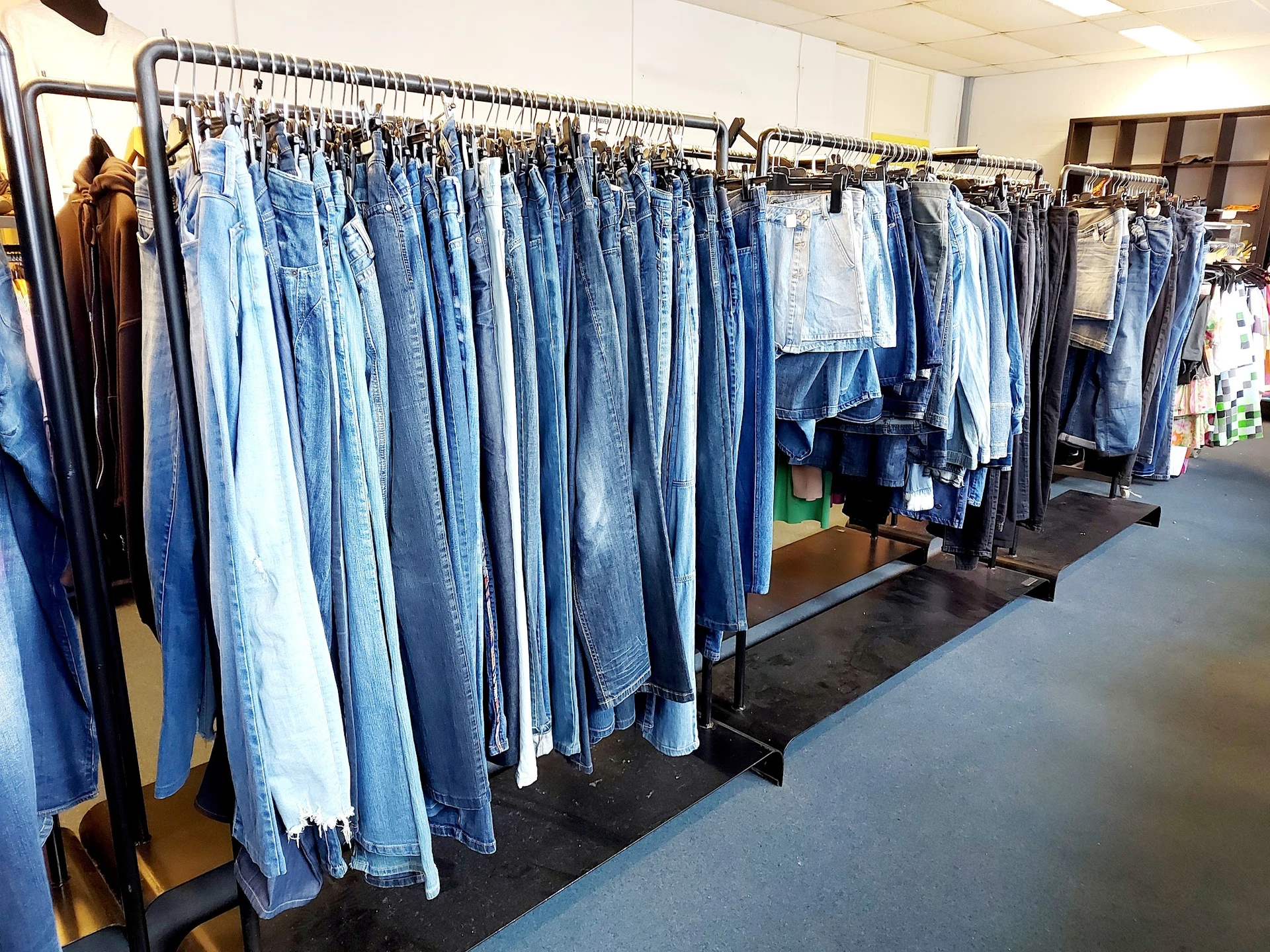 Rekken met grote hoeveelheid tweedehands jeans in verschillende tinten blauw