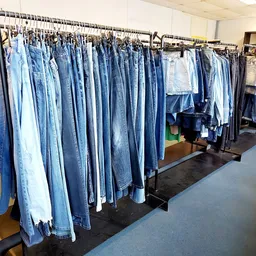 Rekken met grote hoeveelheid tweedehands jeans in verschillende tinten blauw