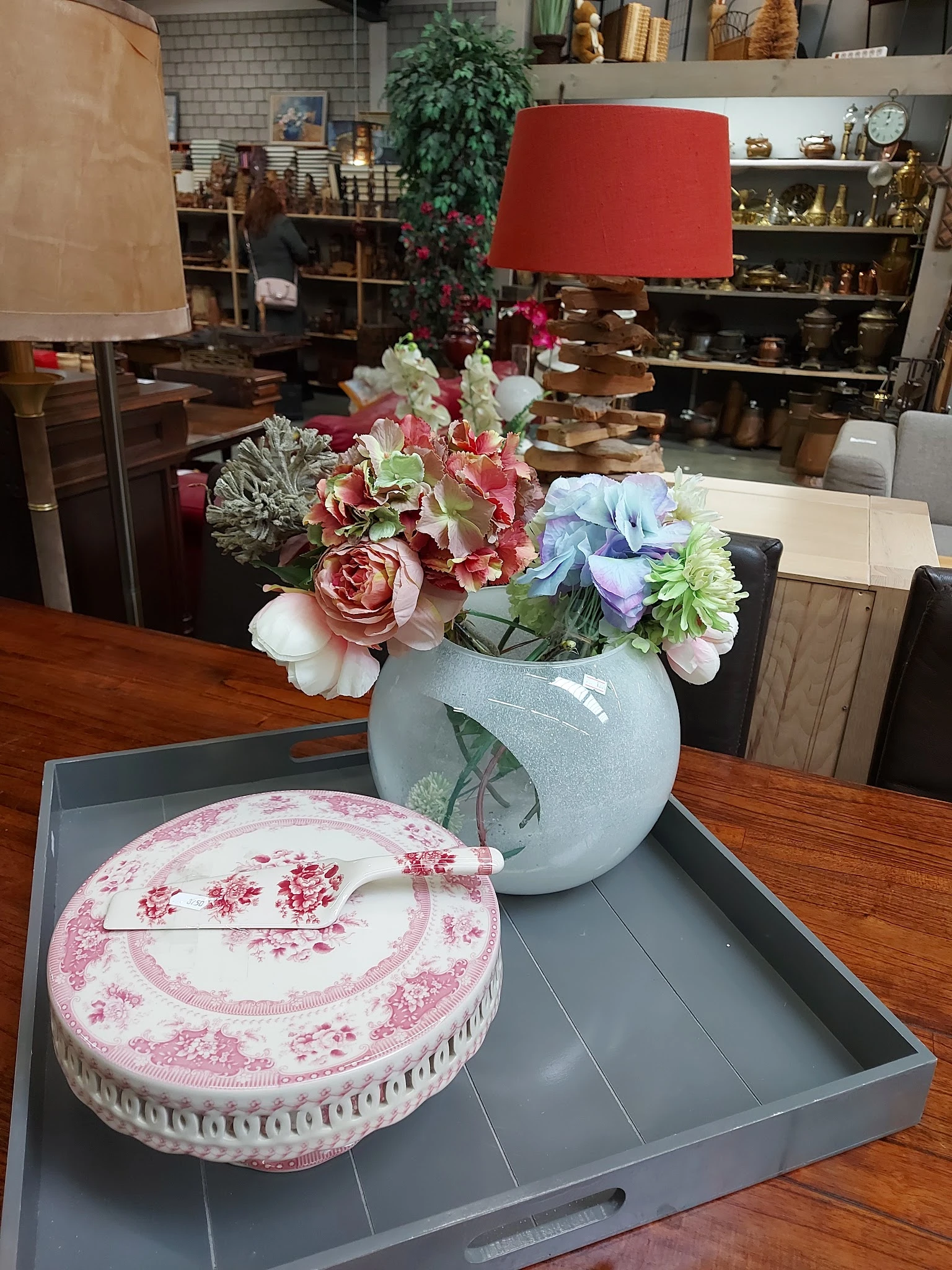Blauwe vaas met roze en witte bloemen op houten tafel naast roze bord