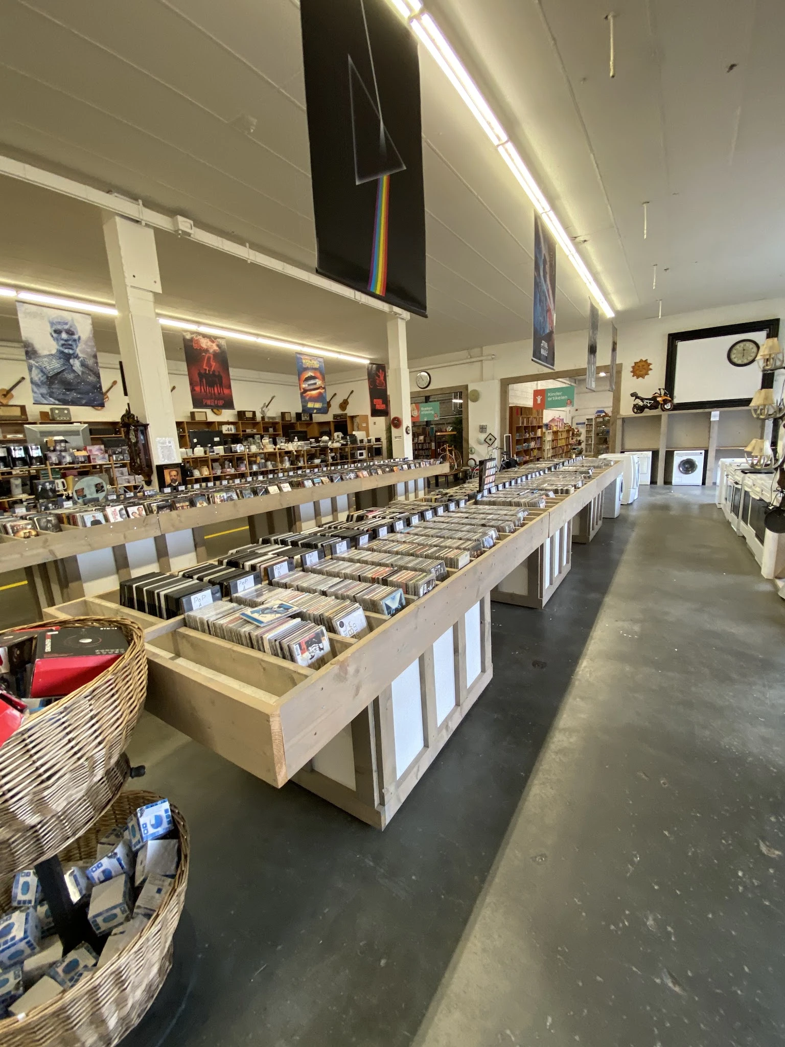 Lange tafels met cd's, vinyl en media uitgestald in kringloopwinkel