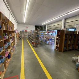 Winkelvloer met gele voetrijnmarkeringen, boekenkasten links, display met collectibles in het midden, houten stellingen recht