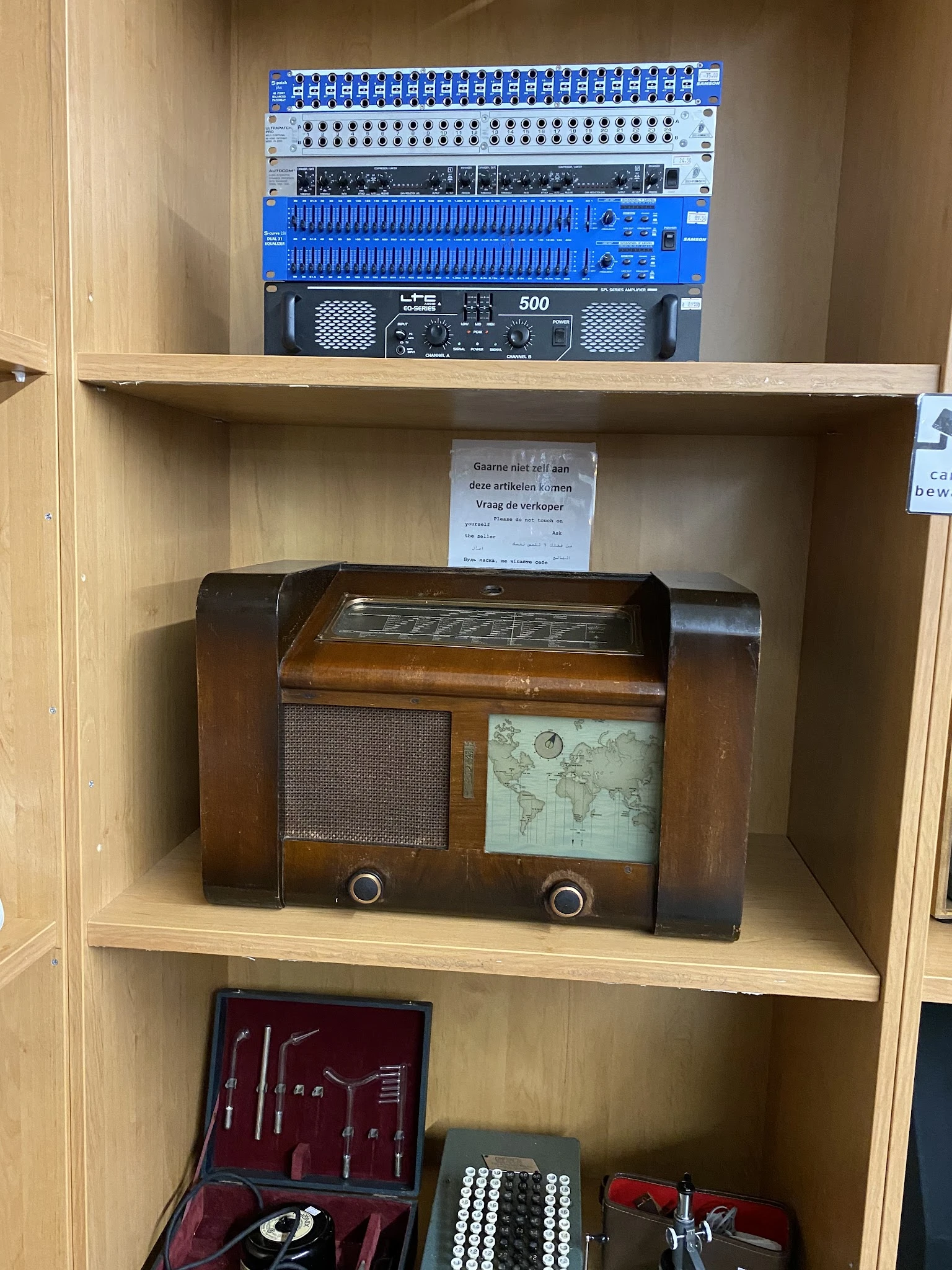 Vintage houten radio met wereldkaart en luidsprekerrooster, staand op winkelplank