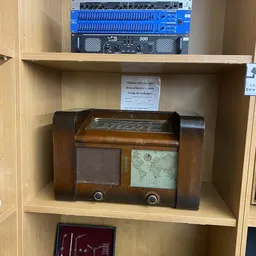 Vintage houten radio met wereldkaart en luidsprekerrooster, staand op winkelplank