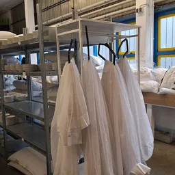 Winkelvloer met stellingen vol witte textiel en beddengoed, blauwe deur op achtergrond