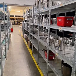 Metalen stellingen met huishoudelijke artikelen en keukenspullen in een kringloopwinkel