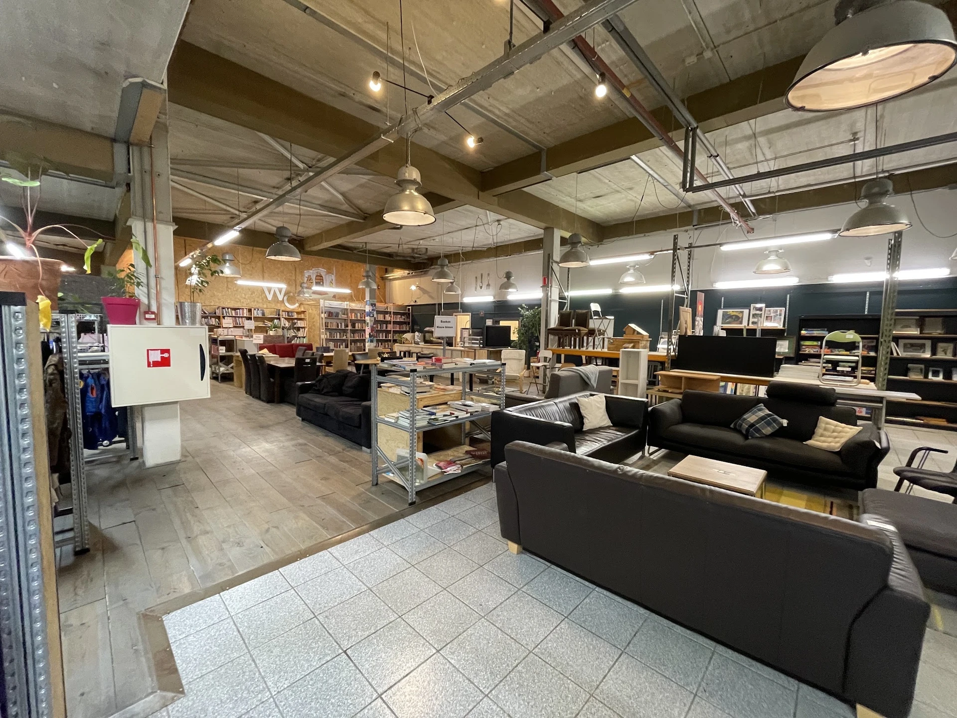 Winkelvloer van kringloopwinkel met zwarte meubels, boekenrekken en diverse spullen