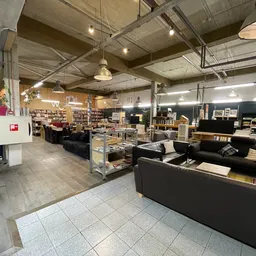 Winkelvloer van kringloopwinkel met zwarte meubels, boekenrekken en diverse spullen