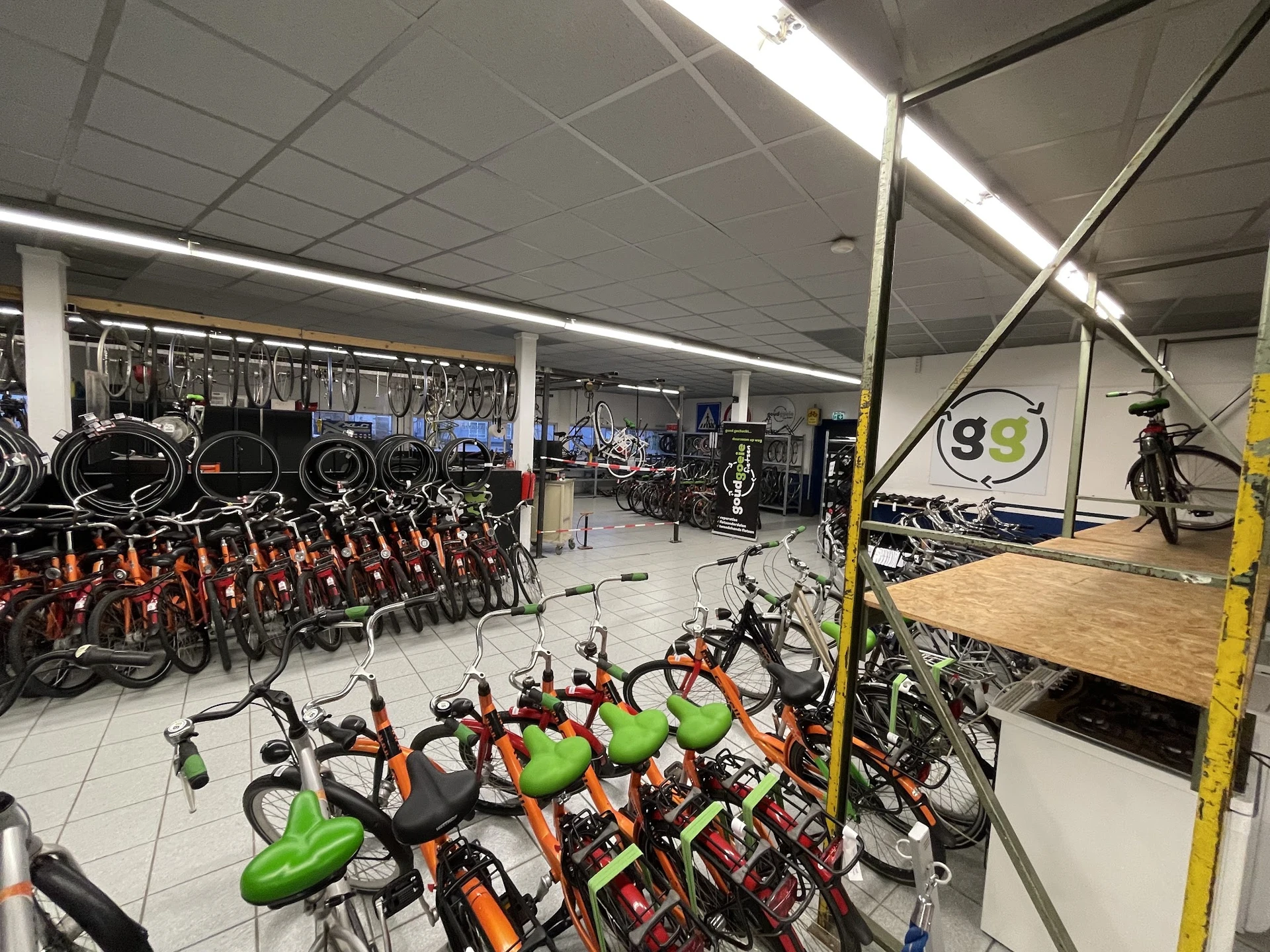 Rijen met tweedehands fietsen met groene en rode zadelkanten in een kringloopwinkel