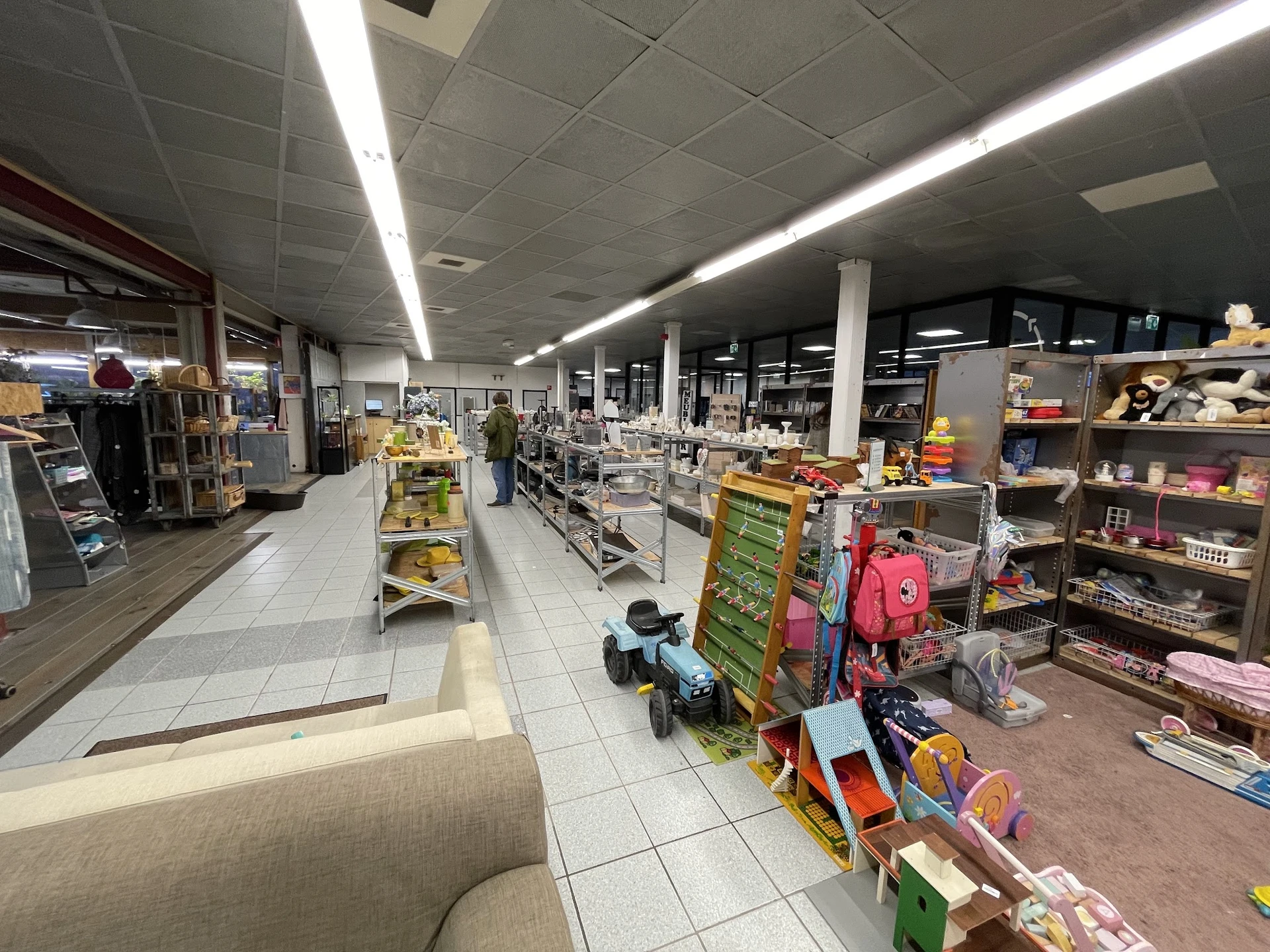 Winkelvloer met stellingen vol speelgoed, kinderartikelen en diverse spullen onder fluorescentverlichting