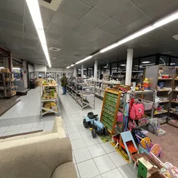 Winkelvloer met stellingen vol speelgoed, kinderartikelen en diverse spullen onder fluorescentverlichting