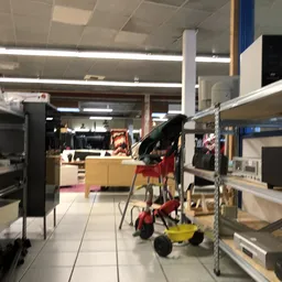 Winkelinterieur met stellingen, rekken met artikelen en een rode winkelwagen op de tegel vloer