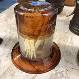 Glazen stolp met houten voet, bevat een wit sculptuur van menselijke figuren