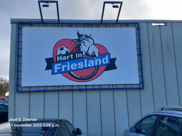 Gevel van kringloopwinkel Hart in Friesland met blauw logo en paardrij-motief op bord