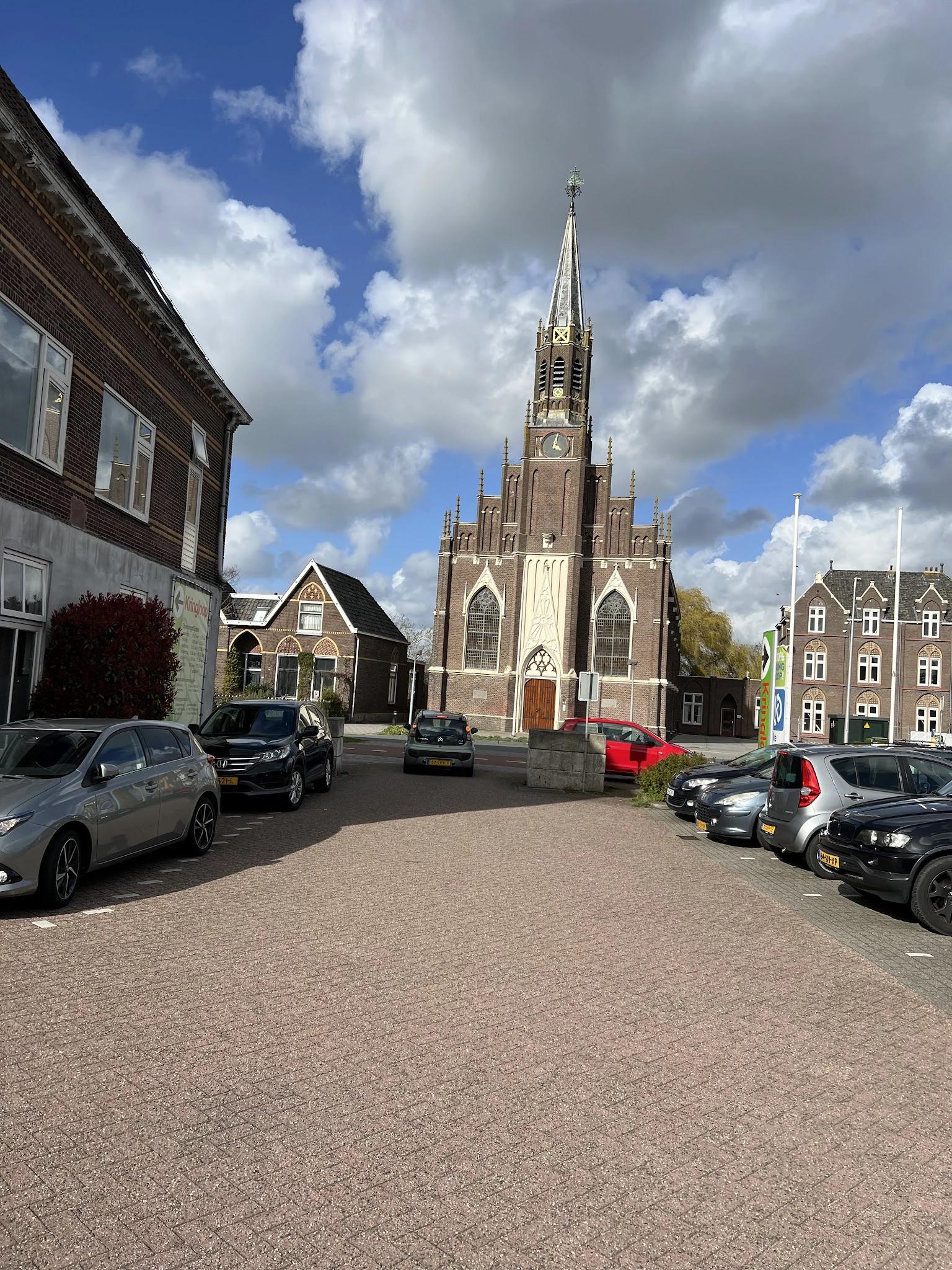 Parkeerplein met auto's en een kerk op de achtergrond, omgeven door kantoorpanden