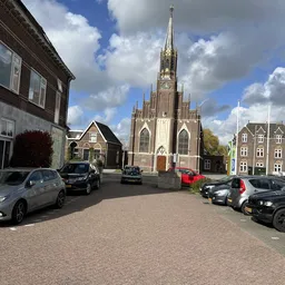 Parkeerplein met auto's en een kerk op de achtergrond, omgeven door kantoorpanden