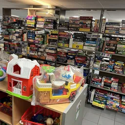 Kinderspeelgoed en bouwblokken op een tafel met kastjes vol dozen met bordspellen en dvd's op de achtergrond