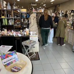 Winkelinterieur met bezoekers tussen stellingen met huishoudelijke artikelen en decoratie