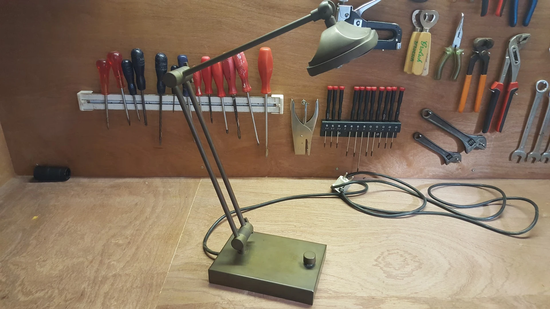 Werkbank met verstelbare lamp en gereedschapswerktuigen opgehangen aan een magneetstrip