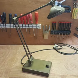 Werkbank met verstelbare lamp en gereedschapswerktuigen opgehangen aan een magneetstrip