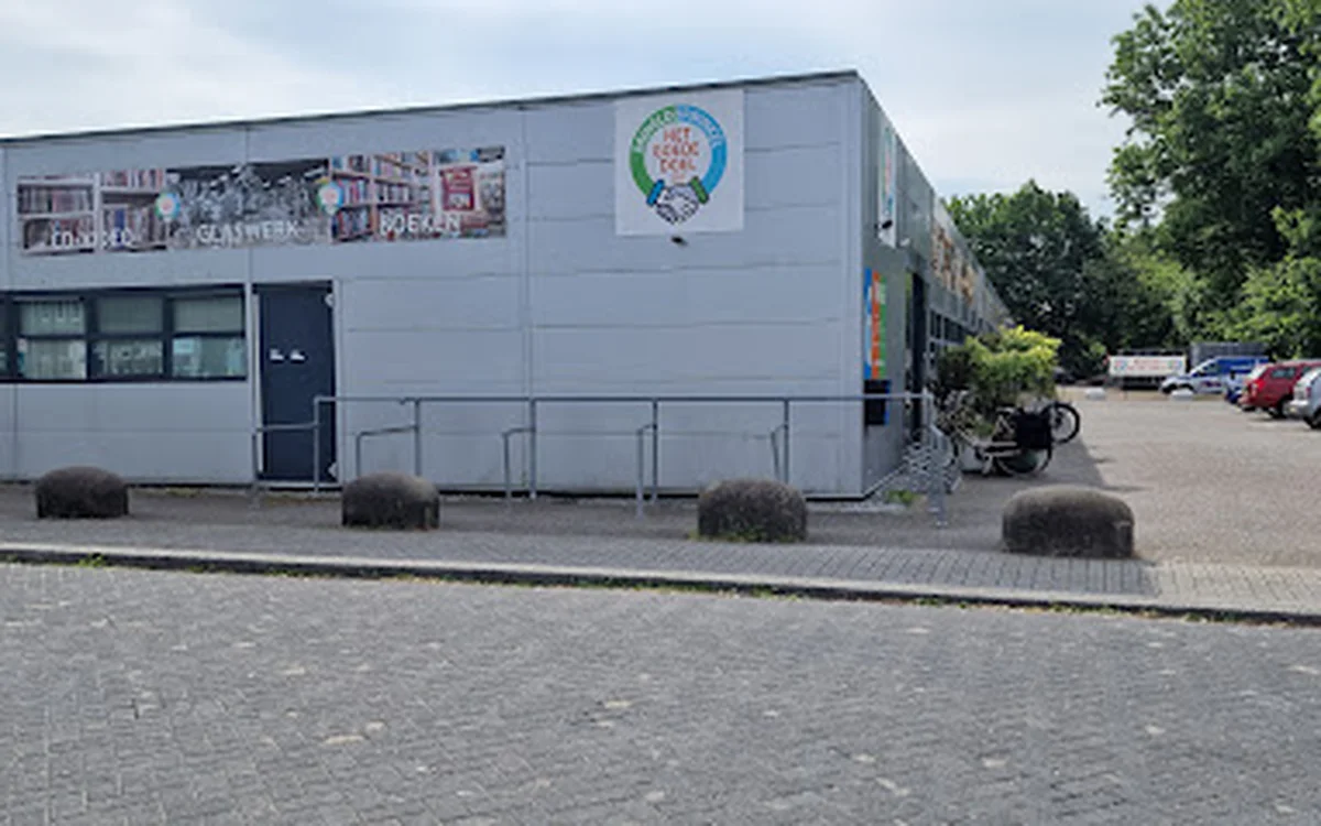 Witte gevel van kringloopwinkel Het Goede Doel met logo, ingang en ramen