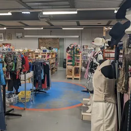 Winkelvloer van kringloopwinkel met kledingrekken, mannequins en winkelrekken met diverse artikelen