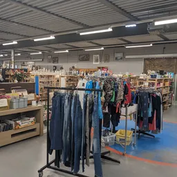 Winkelvloer met kledingrekken, stellingen met artikelen en blauwe vloermarkeringen in een kringloopwinkel